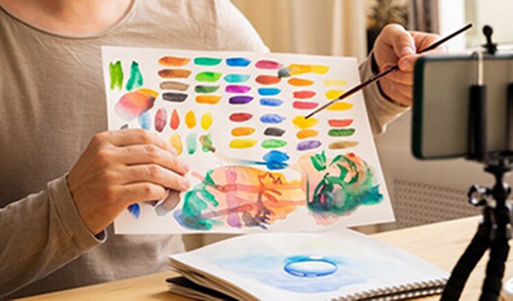 An instructor holding up a watercolor sample to a webcam.