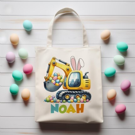 Makerplace by Michaels A tote bag features a cartoon excavator with bunny ears filled with colorful Easter eggs. Surrounding it are pastel eggs on a white wooden surface.