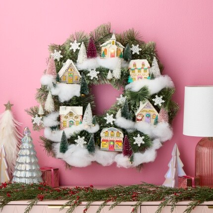 wreath with small houses and fake snow on pink wall