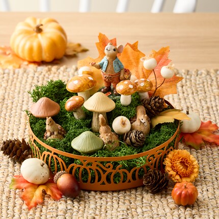 Minature mushroom, orange pumpkins, maple leaves and green moss in an orange display tray 