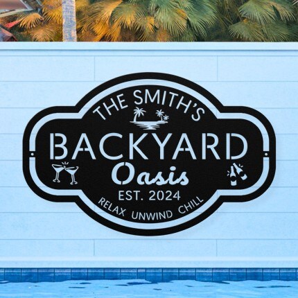 MakerPlace by Michaels Sign reading "The Smith's Backyard Oasis, Est. 2024, Relax Unwind Chill" on a white wall by a pool. Includes cocktail icons, evoking a tropical, relaxed vibe.