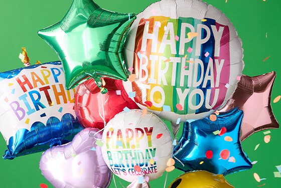 femme en chemise jaune tenant un bouquet de ballons d'anniversaire sur fond vert avec des confettis