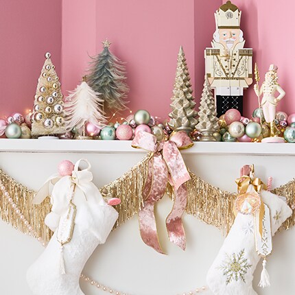 pink wall with white mantle decorate with white stockings and gold accents