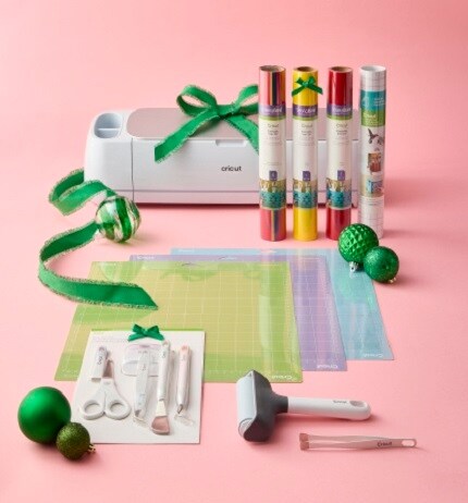 Cricut cutting machine, cutting mats, vinyl and tools on pink background