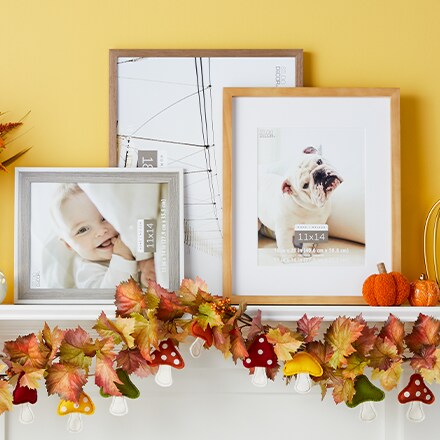 Pumpkin Patch collection: orange decorative garland over a mantel with some photo frames on top.