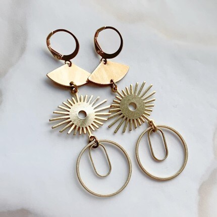MakerPlace by Michaels Pair of gold-tone statement earrings on a pale marble background, featuring sunburst discs, curved fan shapes, and open circular drops for a bold, elegant look.