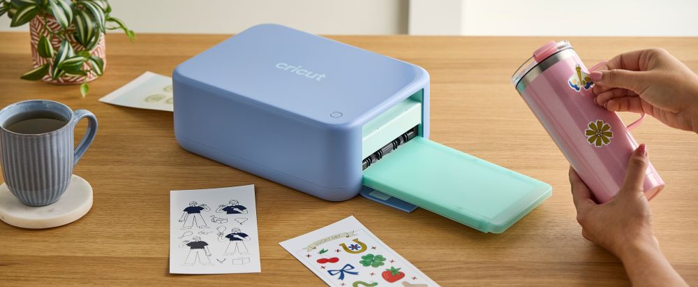 Cricut StickerPix Print + Cut sits on a table surrounded by sticker sheets