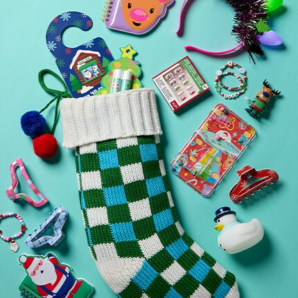notebook, pens, stickers and toys spilling out of a stocking against a teal backdrop