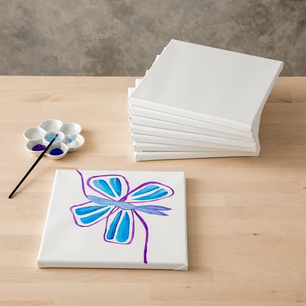 A canvas with a painted flower and a stack of blank canvases behind it