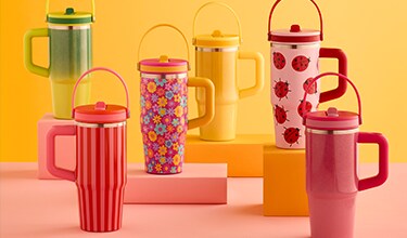 Tumblers with handles against a yellow backdrop. 