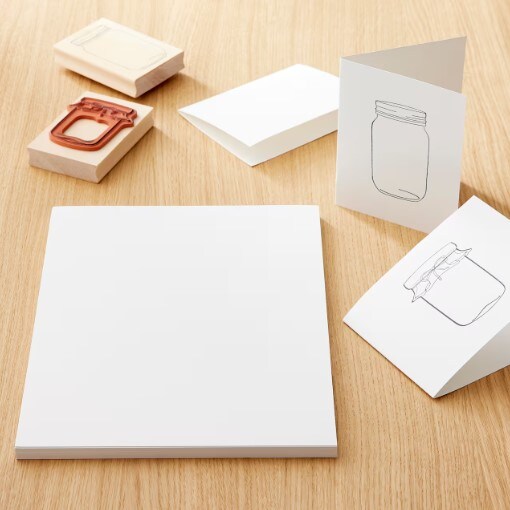 White blank paper sitting on a table with homemade cards and stamps