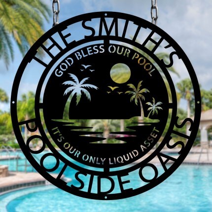 MakerPlace by Michaels Round metal sign with palm trees and a moon silhouette, reading "God Bless Our Pool, It's Our Only Liquid Asset," against a blurry pool background. Tropical vibe.