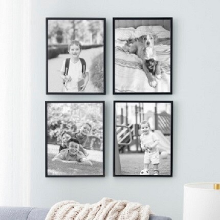 four black frames with black and white photos of children and pets