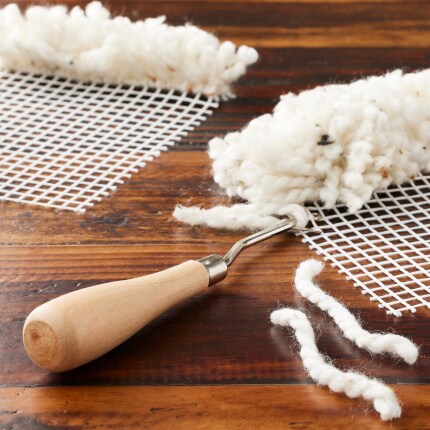 latch hook tool with mesh and white yarn strands with latch hook project