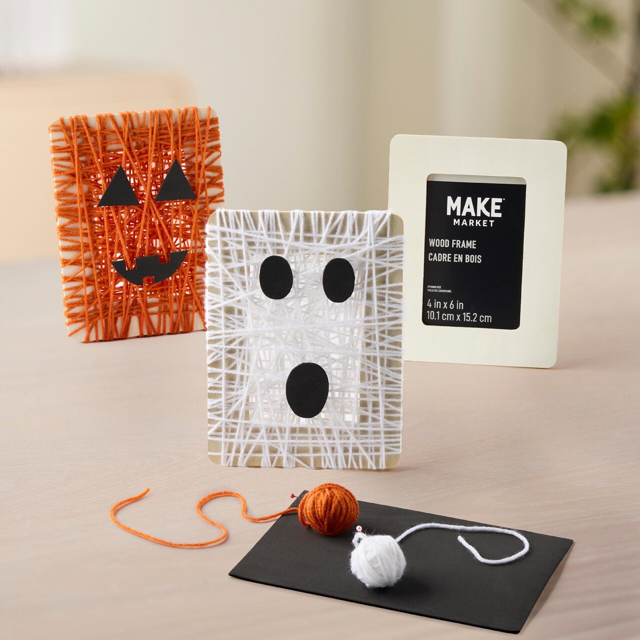 Wooden frames wrapped in orange or white yarn with felt faces attached to create Halloween themed decorations
