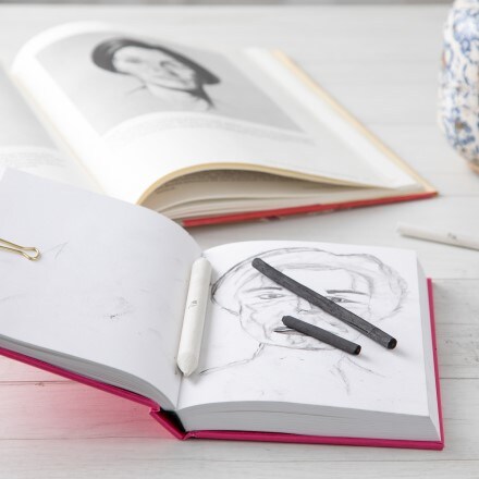 two sketchbooks on table with charcoal sitting on one of them
