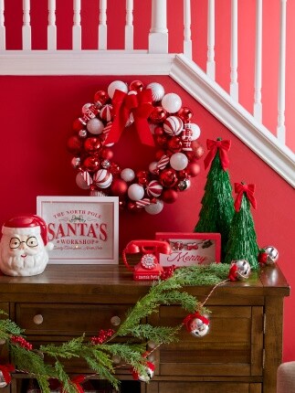 red holiday wreath above table with garland and Christmas decor accents