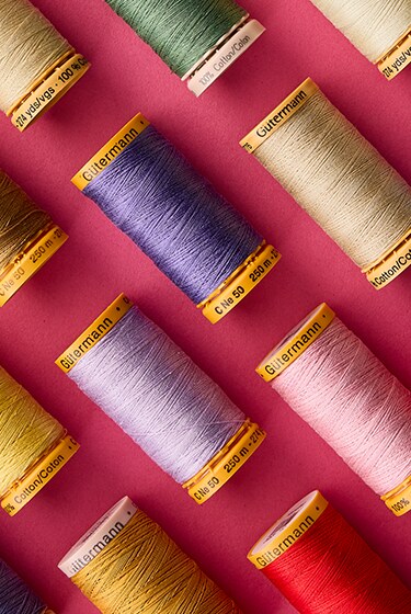 assorted thread spools in diagonal pattern with pink background