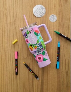 Pink tumbler surrounded by pens