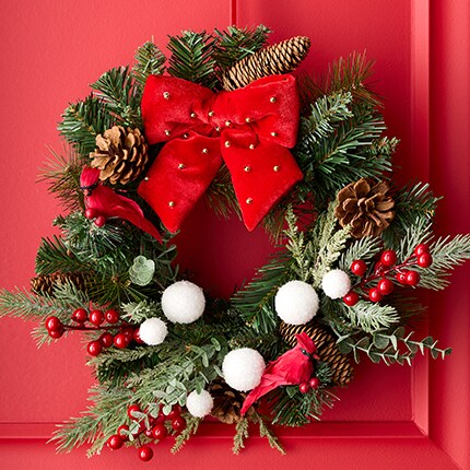 holiday wreath with bobbles and red bow on red door