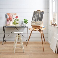 Table with painting on top and Easel holding an unfinished paiting