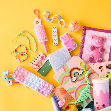 notebook, pens, stickers and toys layed out against a yellow backdrop