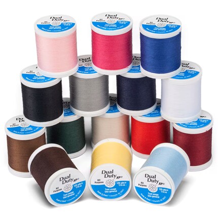 Colorful sewing thread spools are stacked in a pyramid, featuring pink, red, blue, black, white, gray, and yellow cones.
