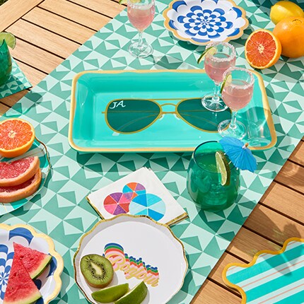 Jonathan Adler party supplies blue and teal colors on a beach towel with sunglasses plate