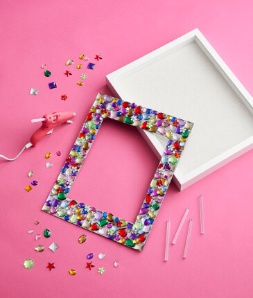 pink glue gun with shadow box frame and mat with gemstones