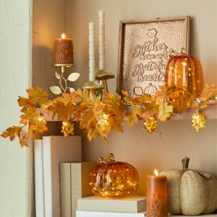 Fall candles and lighting with leaf garland on shelves