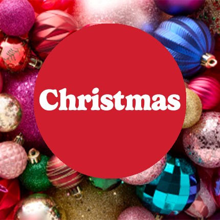 Christmas in white text on red bubble over pile of ornaments