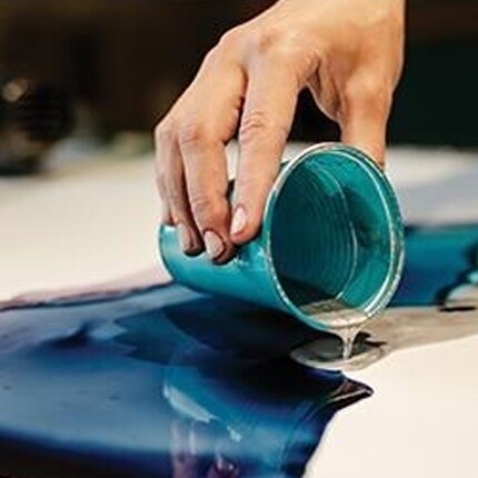 A hand pouring resin onto a surface