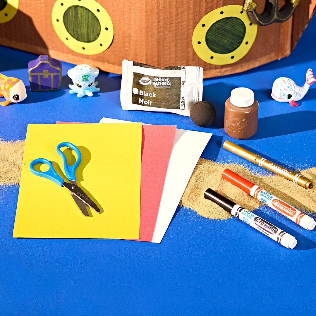 Scissors sitting on contruction paper with markers sitting to the site. 