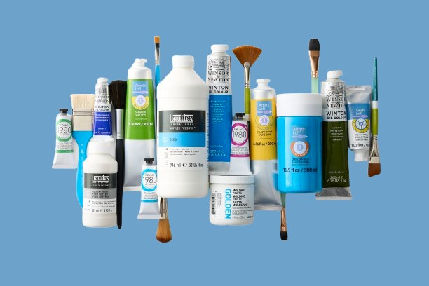 Paint, mediums, and brushes on blue background