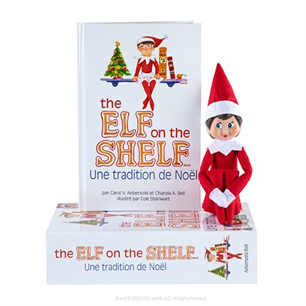 Elf sitting in front of the Elf on the Shelf book.