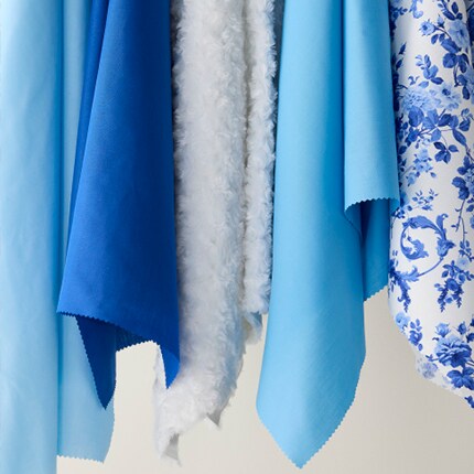 rolls of blue, red, orange and green fabrics with white lattice designs 
