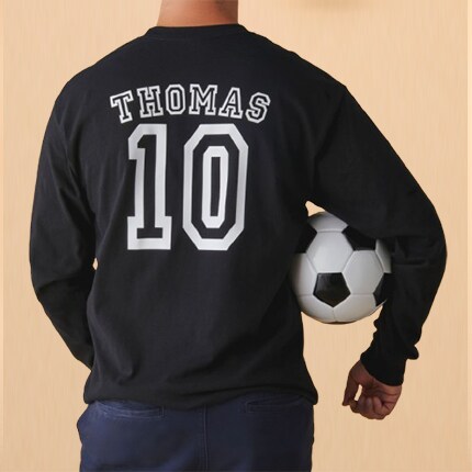 man standing with back turned in black sweatshirt with white numbers and name holding a soccer ball