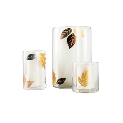three glass hurricane cylinders with leaf decorations