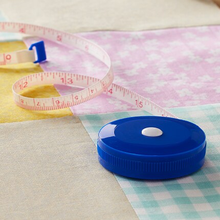 measuring tape with fabric squares on table
