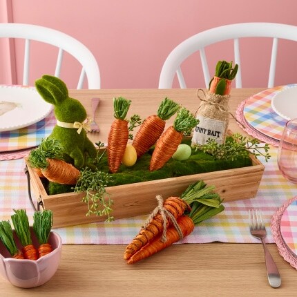 crate with carrot decorations and bunny figures on dining table