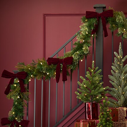 A christmas tree garland and presents on a staircase