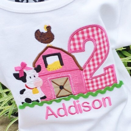 MakerPlace by Michaels Children's shirt with a pink barn, a cute cow, a hen, and a large plaid number two. The name "Addison" is embroidered in pink below.