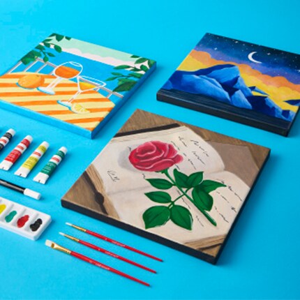 painted canvases with supplies on blue background