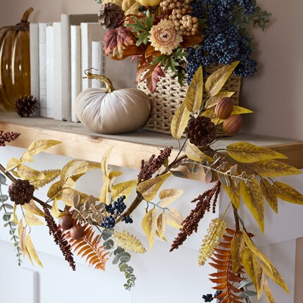 A shelf with books, flowers, garland
