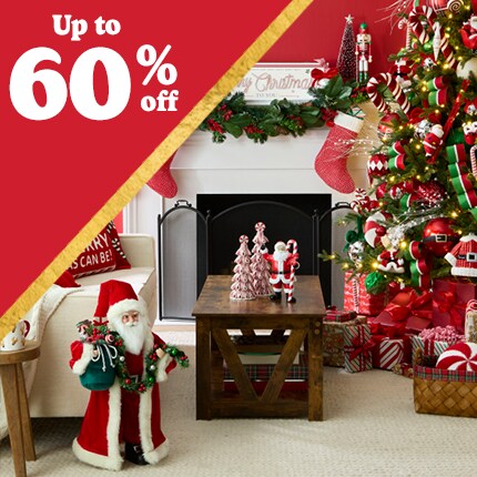 red room with santa and stockings on mantle, with decorated Christmas tree and wood table with ceramic tree accents with 50% off in white text in red triangle