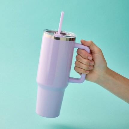 hand holding purple tumbler on blue background