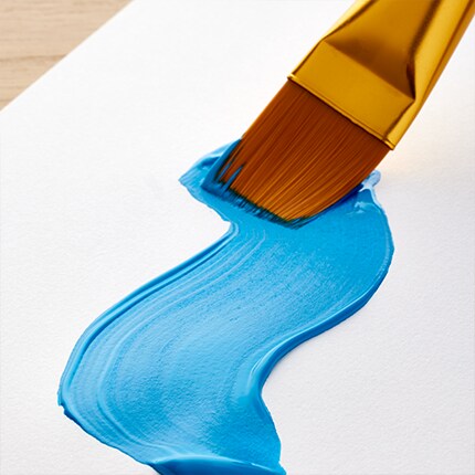 paint brush with blue paint stroke on white paper