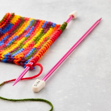 pink knitting needles with rainbow yarn project