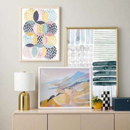 brown floating shelves with gold and black frames and small plant