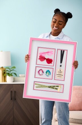 woman holding pink frame of concert pass, sunglasses and photos 